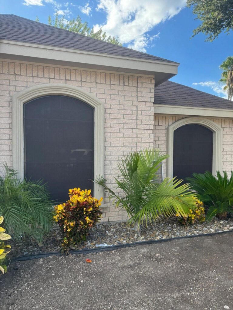 Dark sun screens on the arched windows of a brick home