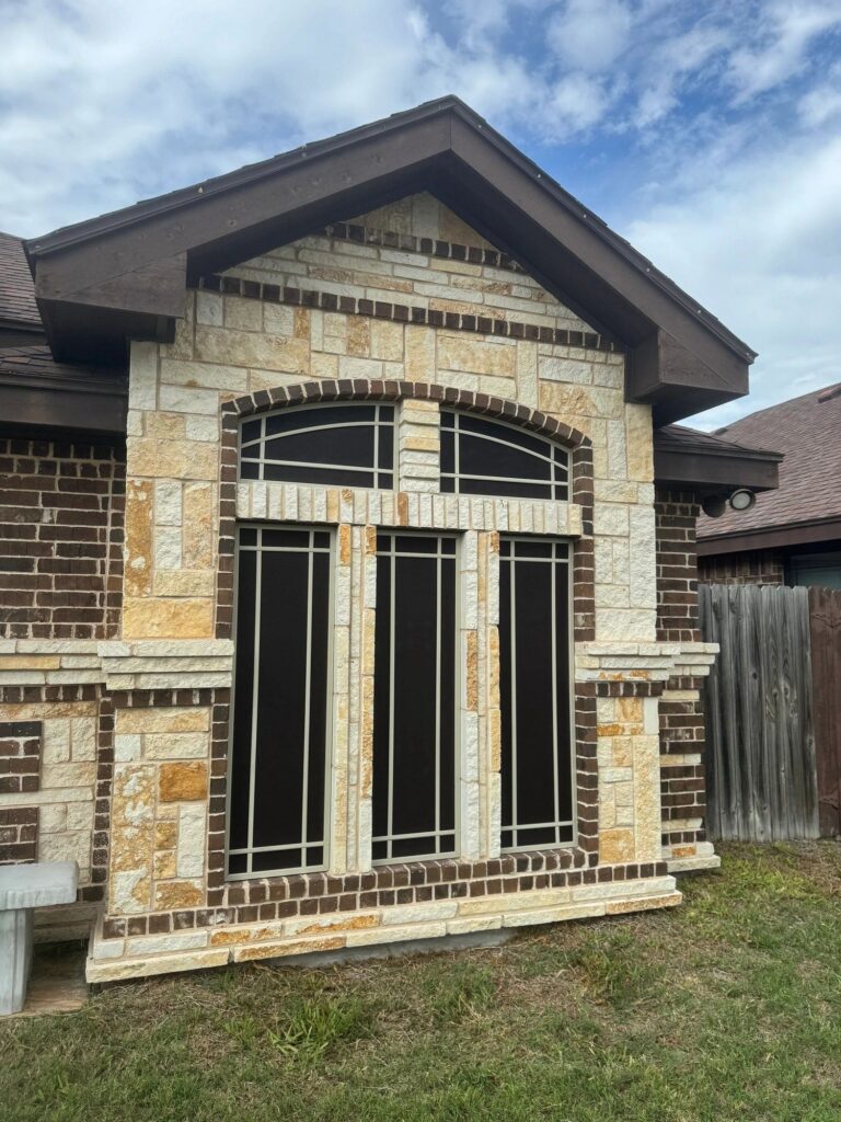 Dark screens on the windows of a stone-front home
