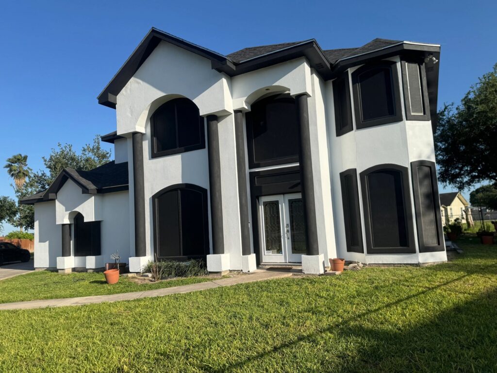 Two-story stucco home with dark screens on its arched windows