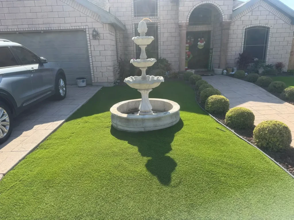 Green turf around a stone fountain in a front yard